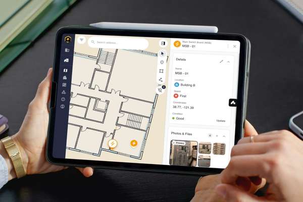 Person holds a tablet displaying an architectural floor plan map with a left toolbar and a right detail panel for the project/room information.